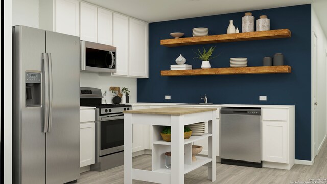 kitchen featuring white cabinetry, sink, light wood-type flooring, and appliances with stainless steel finishes