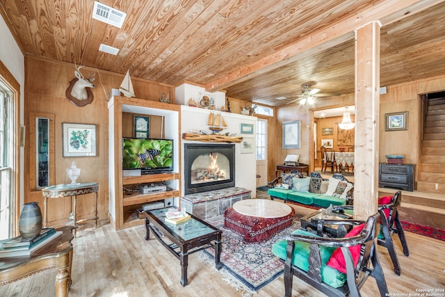 living room featuring light hardwood / wood-style floors, wood walls, ceiling fan, and wood ceiling