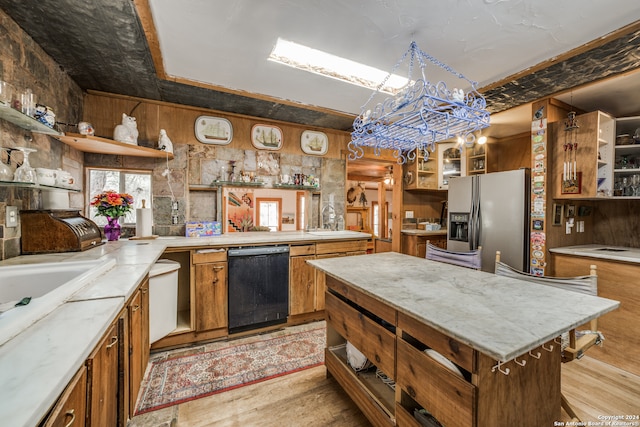 kitchen with a kitchen island, stainless steel fridge with ice dispenser, black dishwasher, and light hardwood / wood-style flooring