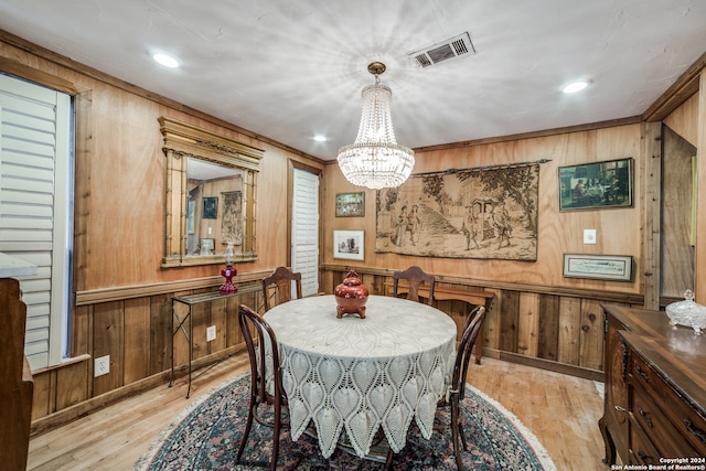 dining room featuring wood walls, light wood-type flooring, and a chandelier