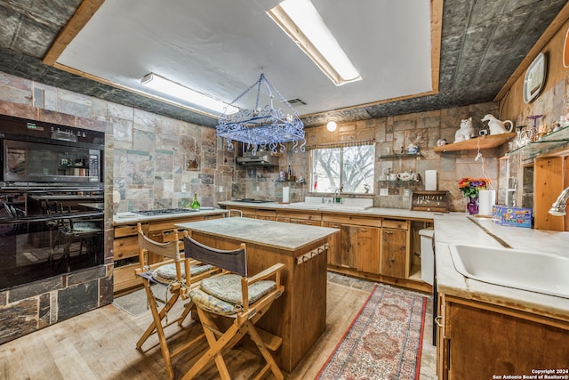 kitchen featuring light hardwood / wood-style floors, sink, stainless steel gas stovetop, double oven, and a center island