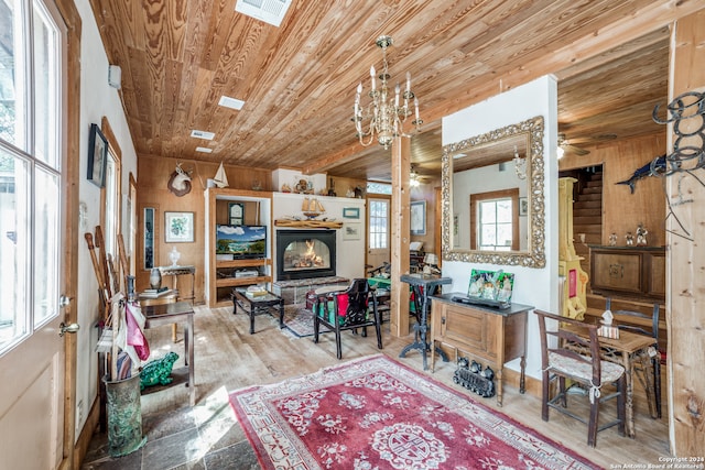 living room featuring wood walls, wood ceiling, wood-type flooring, and ceiling fan with notable chandelier