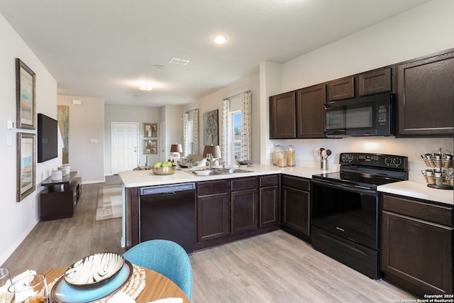 kitchen with black appliances, dark brown cabinets, sink, kitchen peninsula, and light hardwood / wood-style flooring