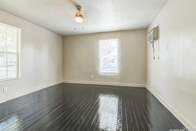 spare room with ceiling fan, a wall unit AC, and dark hardwood / wood-style floors