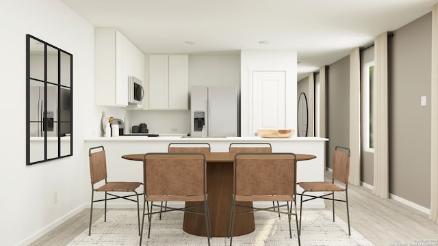 kitchen with white cabinets, white fridge with ice dispenser, a breakfast bar, and light hardwood / wood-style flooring