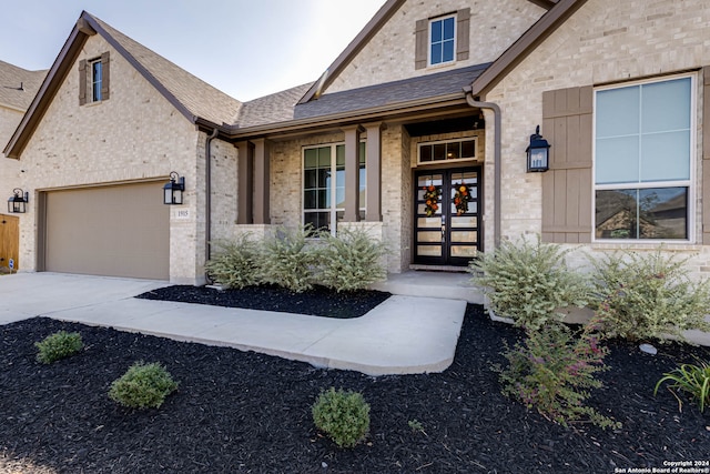 view of exterior entry with a garage and french doors