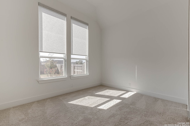 unfurnished room featuring light colored carpet and vaulted ceiling