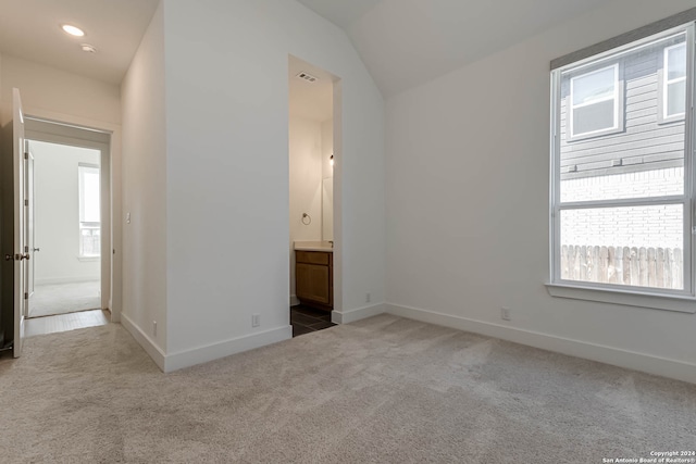 carpeted spare room featuring a wealth of natural light and vaulted ceiling