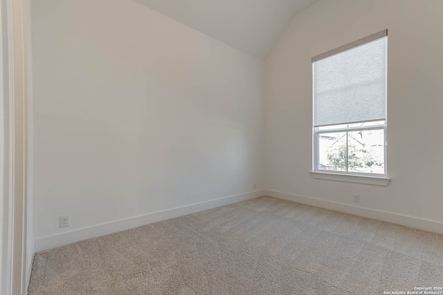 carpeted empty room with lofted ceiling