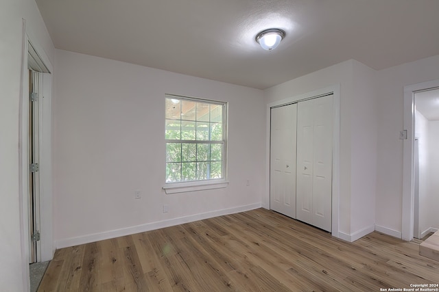 unfurnished bedroom with light hardwood / wood-style flooring and a closet