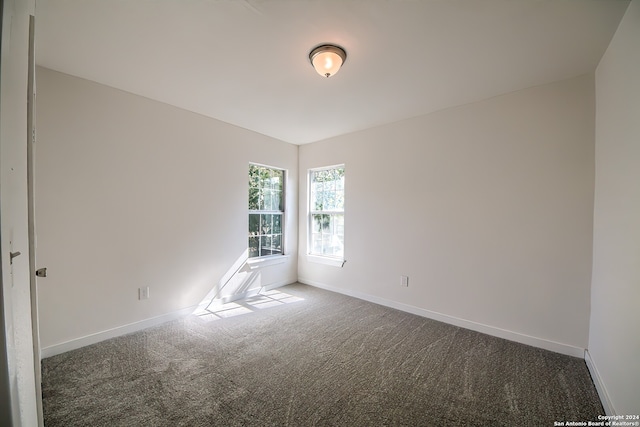 spare room with dark colored carpet