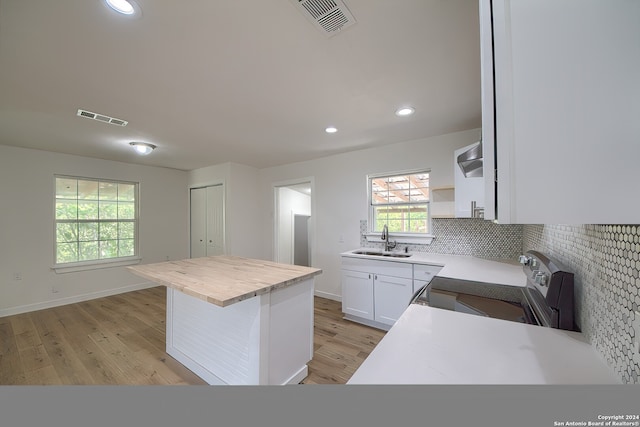 kitchen featuring light hardwood / wood-style floors, white cabinetry, sink, stainless steel range with electric cooktop, and a kitchen island