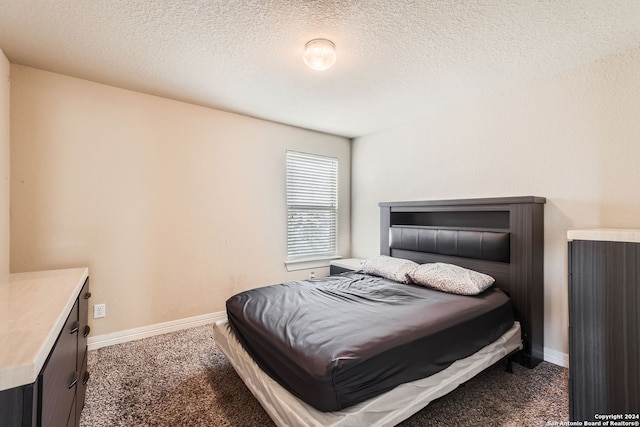 bedroom with dark colored carpet and a textured ceiling