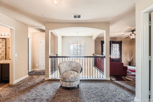 hall featuring carpet flooring and a textured ceiling