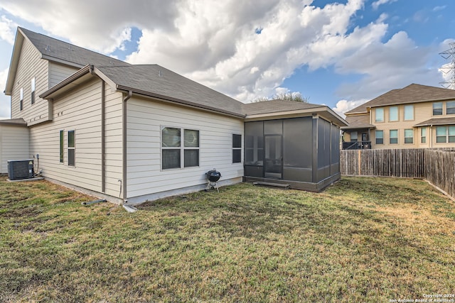 back of house featuring central air condition unit, a lawn, and a sunroom