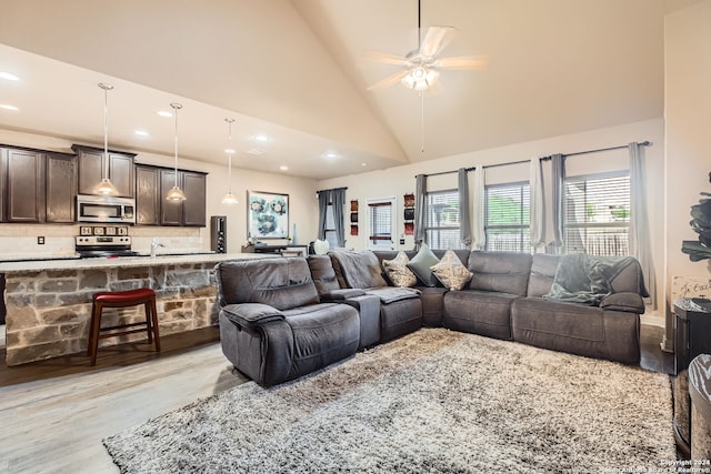 living room featuring ceiling fan, light wood-type flooring, and high vaulted ceiling