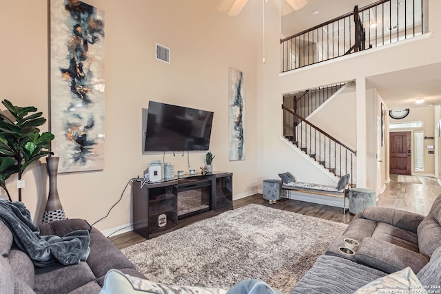 living room featuring a high ceiling, hardwood / wood-style flooring, and ceiling fan