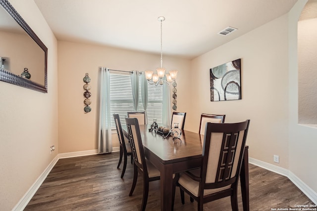 dining space with dark hardwood / wood-style floors and a notable chandelier