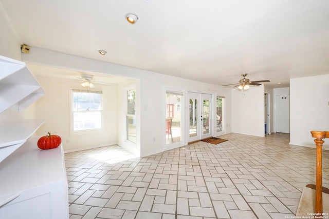 unfurnished living room featuring a wealth of natural light, ceiling fan, and french doors