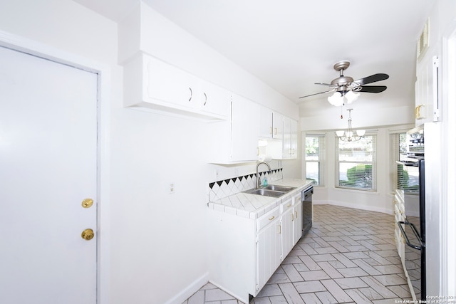 kitchen with tile countertops, dishwasher, sink, white cabinetry, and black oven