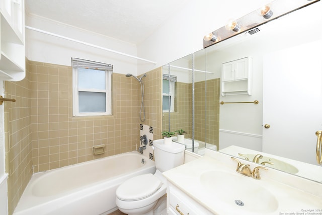 full bathroom featuring toilet, vanity, tiled shower / bath, and a textured ceiling