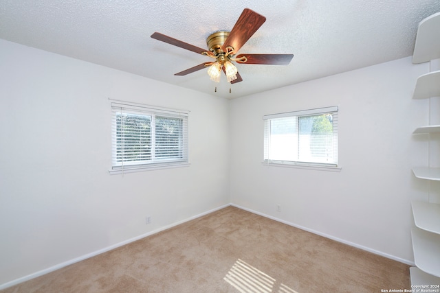 carpeted empty room featuring a textured ceiling, ceiling fan, and plenty of natural light