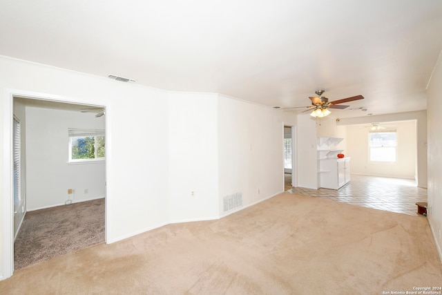 carpeted empty room with a wealth of natural light, ceiling fan, and crown molding