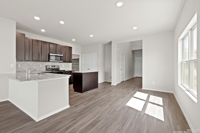 kitchen featuring light stone countertops, sink, a wealth of natural light, kitchen peninsula, and appliances with stainless steel finishes