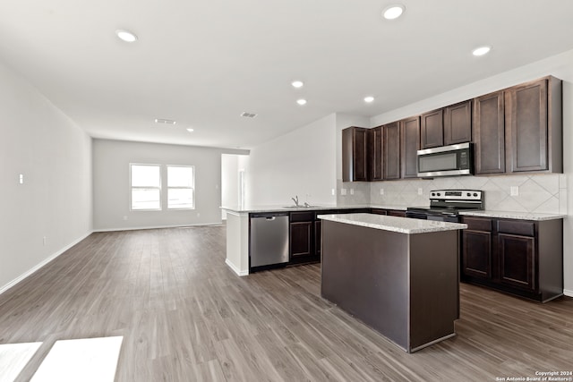 kitchen featuring decorative backsplash, dark brown cabinets, stainless steel appliances, sink, and hardwood / wood-style floors