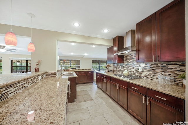 kitchen with stainless steel gas cooktop, hanging light fixtures, a healthy amount of sunlight, and wall chimney range hood