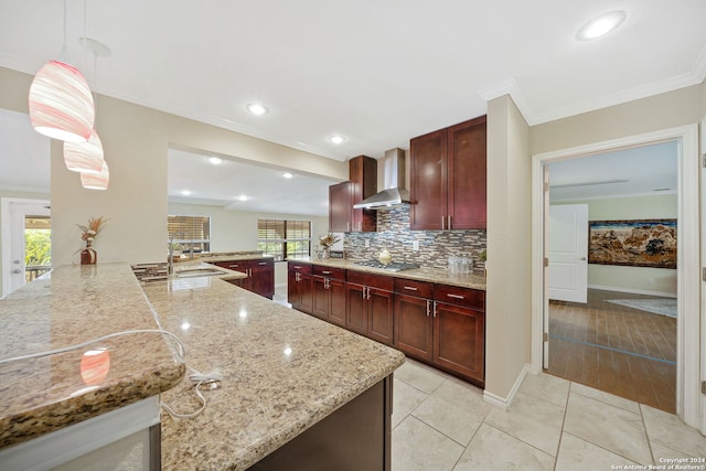 kitchen featuring kitchen peninsula, wall chimney exhaust hood, hanging light fixtures, and light stone counters