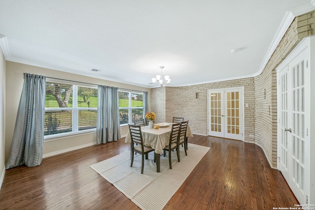 dining room featuring brick wall, ornamental molding, french doors, a notable chandelier, and dark hardwood / wood-style flooring