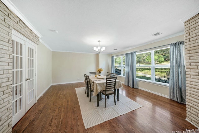 dining room featuring dark wood-type flooring, a chandelier, a textured ceiling, and ornamental molding