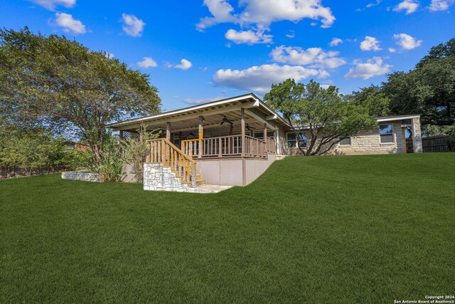 rear view of house featuring ceiling fan and a yard