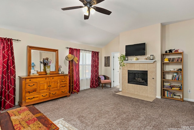 living room with a tiled fireplace, carpet floors, ceiling fan, and vaulted ceiling