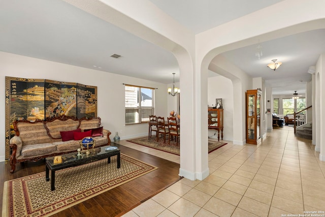 living room featuring ceiling fan with notable chandelier, a healthy amount of sunlight, and light wood-type flooring