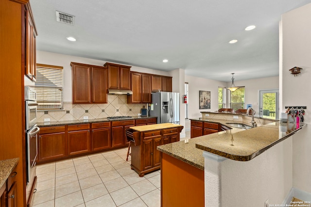 kitchen featuring stainless steel appliances, a center island, kitchen peninsula, sink, and dark stone countertops