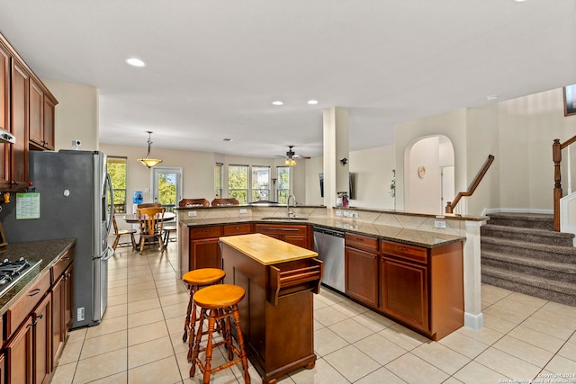 kitchen featuring stainless steel appliances, a center island, kitchen peninsula, sink, and a kitchen breakfast bar