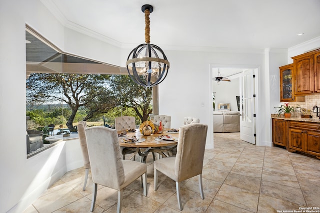 dining room featuring ceiling fan with notable chandelier, sink, and crown molding