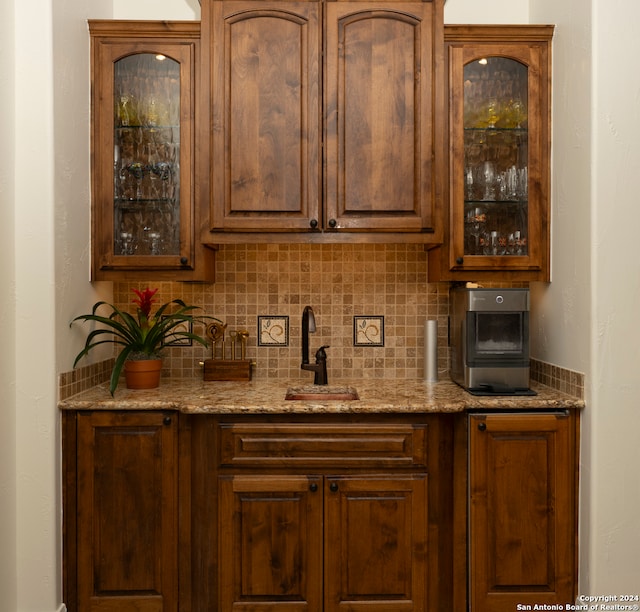 bar with tasteful backsplash, sink, and light stone counters