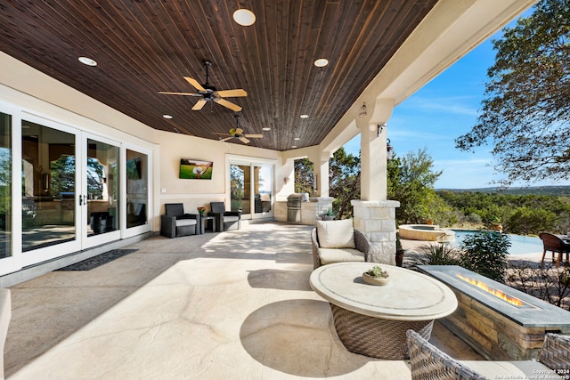 view of patio with french doors, an in ground hot tub, an outdoor kitchen, an outdoor fire pit, and ceiling fan