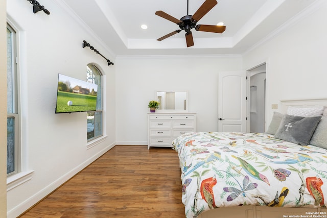 bedroom featuring ornamental molding, dark wood-type flooring, ceiling fan, and a raised ceiling