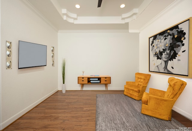 living area featuring a tray ceiling, wood-type flooring, and ornamental molding