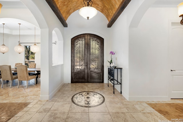 foyer entrance featuring vaulted ceiling, french doors, and ornamental molding