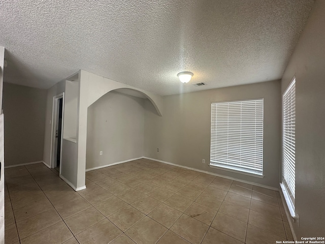 unfurnished room with light tile patterned flooring and a textured ceiling