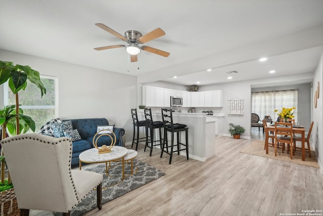 living room with light hardwood / wood-style flooring and ceiling fan