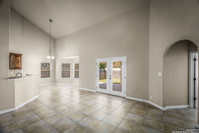 unfurnished living room featuring french doors, high vaulted ceiling, and light tile patterned flooring