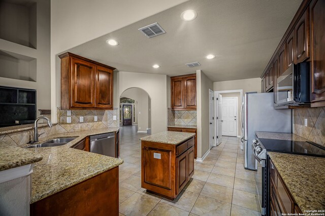 kitchen with decorative backsplash, sink, light stone counters, and appliances with stainless steel finishes