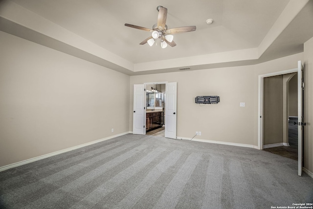 empty room featuring light colored carpet, ceiling fan, and a raised ceiling