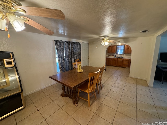 tiled dining space with a textured ceiling and ceiling fan